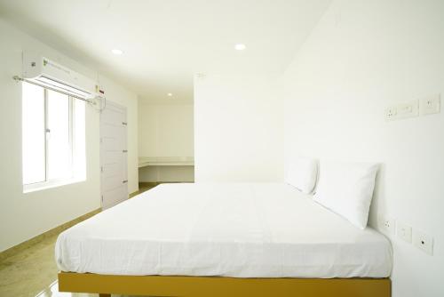 a white bedroom with a large bed and a window at Quilon Residency Kundara in Perumanseri