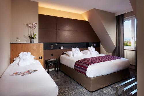 een hotelkamer met 2 bedden en een raam bij Hotel L'Europe in Colmar