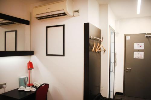 a room with a desk and a phone on a wall at Lazdana Hotel Kuala Lumpur in Kuala Lumpur