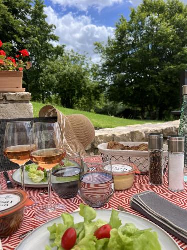 a table with glasses of wine and a plate of food at Les Arches du Lac, spa et piscine intérieure chauffée in Saint-Martin-lès-Langres