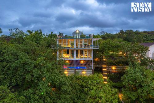 a large building with lights in the trees at The Glasscape by StayVista - Hillside getaway with Pool and Indoor games in Nashik