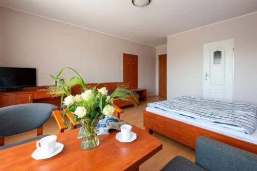 a bedroom with a bed and a table with a vase of flowers at Baltic Neptun in Jastrzębia Góra