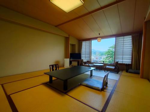 ein Wohnzimmer mit Tisch und Stühlen und einem Fenster in der Unterkunft Kameya Ean in Izunokuni