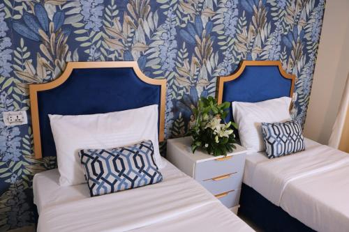 two beds in a room with blue and white wallpaper at New Rafi Hotel in Amman