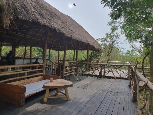 a hut with a bench and a table on a deck at Topi Lodge in Queen Elizabeth National Park