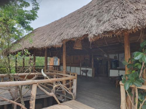 a hut with a thatched roof and a wooden deck at Topi Lodge in Queen Elizabeth National Park