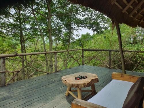 a wooden deck with a table and a bench at Topi Lodge in Queen Elizabeth National Park
