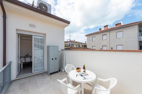 a patio with a white table and chairs on a balcony at Suite Ondina Viareggio Apartments in Viareggio
