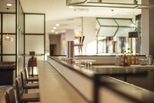 a restaurant with a bar with chairs around it at Holiday Inn - the niu, Leo Nuremberg by IHG in Nürnberg