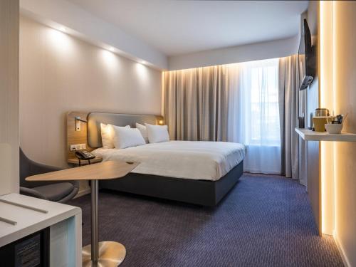 ディーゲムにあるHoliday Inn Express Brussels - Airport by IHGのベッドとテーブルが備わるホテルルームです。