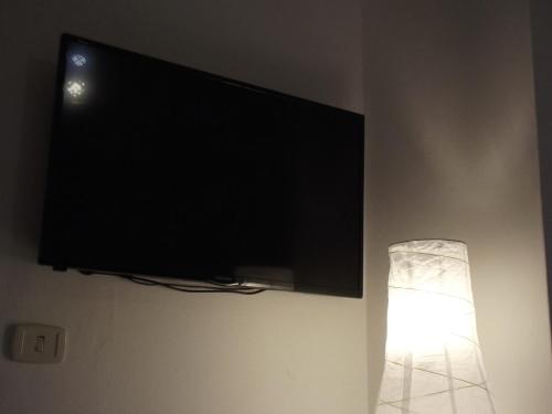 a flat screen tv hanging on a wall with a lamp at Pisa Center in Pisa