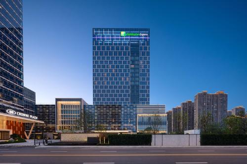 a tall building with a green sign on it in a city at Holiday Inn Express Suzhou East Taihu by IHG in Suzhou
