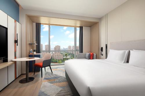 a hotel room with a bed and a desk and a window at Holiday Inn Express Suzhou East Taihu by IHG in Suzhou
