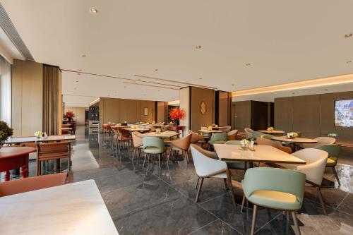 a restaurant with tables and chairs in a room at Holiday Inn Express Hangzhou Jiangnan by IHG in Hangzhou