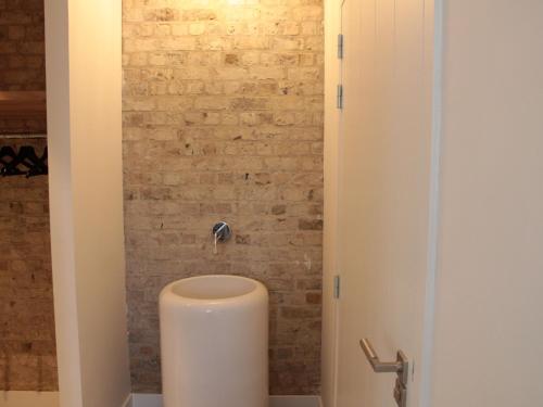a toilet in a bathroom with a brick wall at Villa in Zealand near Dutch Flanders Coast in Zuidzande