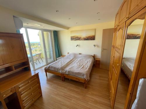 a bedroom with a bed and a large window at Laguna Sunset Appatments, sea and mountain view in Primorsko