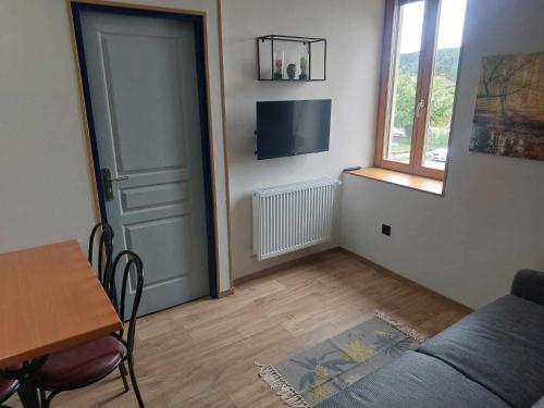 a living room with a couch and a table and a window at Studio avec cuisine in Raddon-et-Chapendu