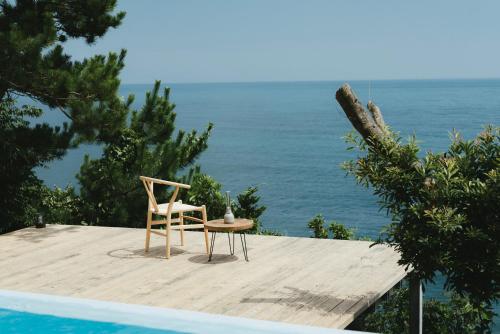 a chair and table on a wooden deck next to the ocean at 琴ヶ浜の渚 in Geisei