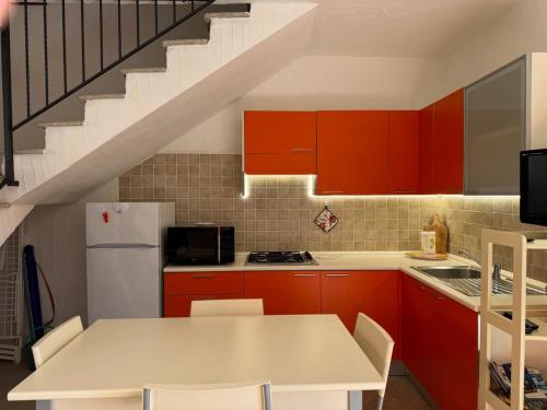 a kitchen with red cabinets and a white refrigerator at Villa Arianna - Porto Pino in SantʼAnna Arresi