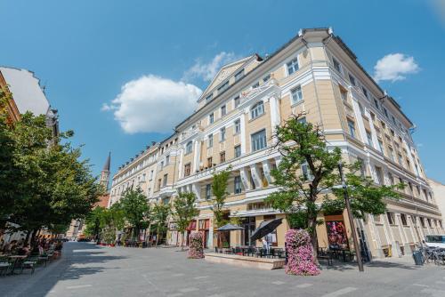 a large building on a street with trees in front at Old Town Square Apartments Cluj in Cluj-Napoca