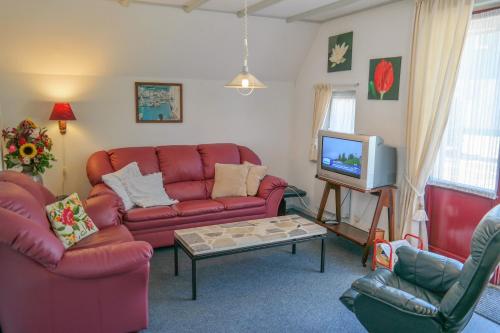 a living room with a red couch and a tv at Dike House Affordable 6-Person Holiday Home Near the Sea Dike in Anjum