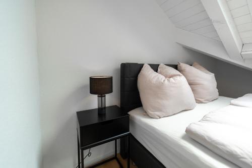 a bed with white pillows and a lamp on a side table at Wohnung mit Extraklasse an fantastischer Lage! in Winterthur
