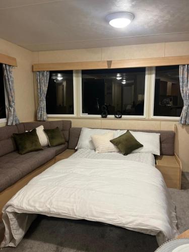 a large bed in a room with a couch at 3 Bedroom Caravan - Sleeps 8 - Parking Wifi Pool in Clacton-on-Sea