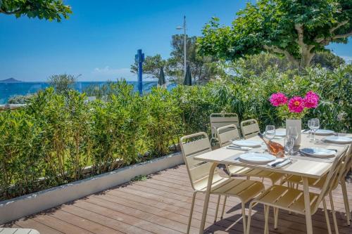 une table blanche avec des chaises et des fleurs sur une terrasse dans l'établissement Aura Plage Appartement Sunrise, à Roquebrune-sur Argens