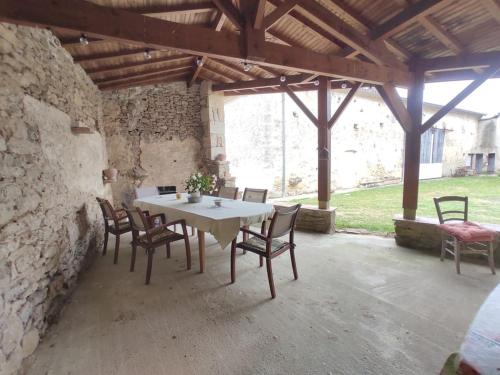 une table et des chaises blanches dans un bâtiment en pierre dans l'établissement Maison Authentique près de La Réole, à Loubens
