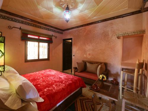a bedroom with a red bed and a couch at Ouirgane Ecolodge in Ouirgane
