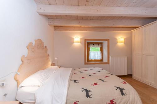 Un dormitorio con una gran cama blanca con cabecero de madera. en Casa Alessandra, en Falcade