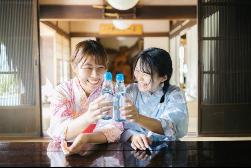 two women sitting at a table holding up glasses at The Ninja Mansion in Toyota