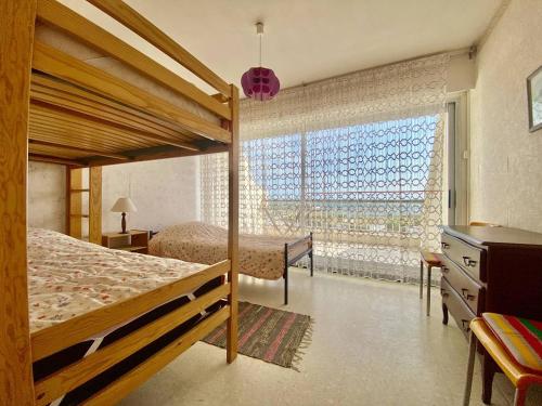 une chambre avec deux lits et une grande fenêtre dans l'établissement PORT CAMARGUE - APPARTEMENT 4 PERSONNES VUE SUR MER - 2 TERRASSES - PARKING, au Grau-du-Roi