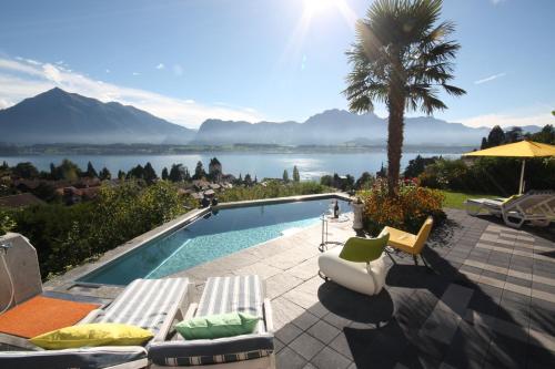 a swimming pool with lounge chairs and a palm tree at Otium-Oberhofen in Oberhofen am Thunersee