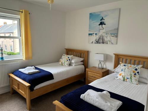 a bedroom with two beds and a lighthouse on the wall at Sunrise Cottage with on-site swimming and sauna in Filey