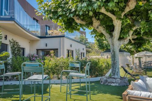 un groupe de chaises assises sous un arbre dans l'établissement Aura plage Appartement Aura Blue, à Roquebrune-sur Argens