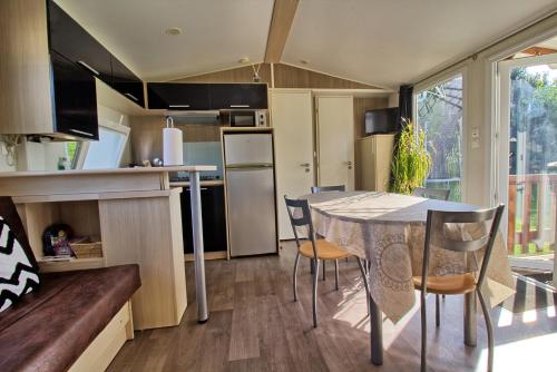 a kitchen and dining room with a table and chairs at Mobilhome 3 chambres 6 personnes in Saint-Loup
