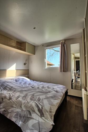 une chambre avec un grand lit avec une fenêtre dans l'établissement Mobilhome 3 chambres 6 personnes, à Saint-Loup