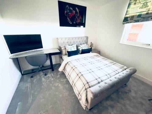 a bedroom with a bed and a desk and a television at Healum Retreat - 3BR Apartment Southall in Southall