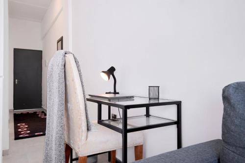 a table with a lamp and a chair with a desk at The Base Apartment in Johannesburg
