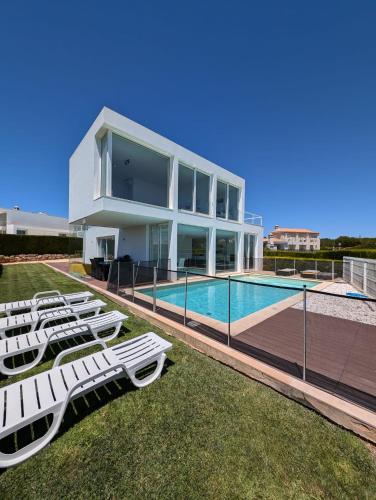 a house with a swimming pool and lounge chairs at White Beach Villa in Sagres
