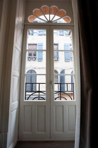 une porte blanche avec une fenêtre en face d'un bâtiment dans l'établissement Chez Juliette, proche Place Nationale avec parking, à Montauban