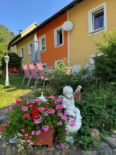 a garden with a statue and flowers in front of a house at PilgerRosenhof in Maria Taferl