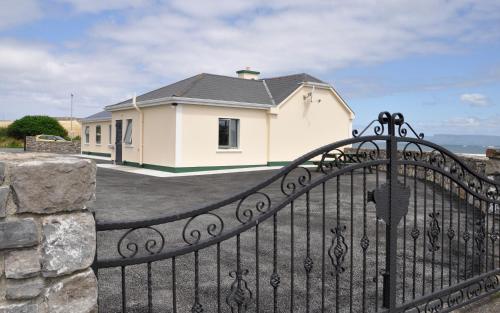a black iron gate with a house in the background at The Waters Edge in Aughris