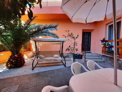 a patio with a bed and a table and chairs at Villa rosa nel cuore di Porto Azzurro in Porto Azzurro