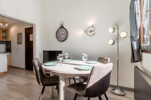 une salle à manger avec une table, des chaises et une horloge murale dans l'établissement Appt Donna - Chamonix Centre, à Chamonix-Mont-Blanc