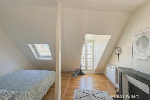 une chambre mansardée avec un lit et une fenêtre dans l'établissement Flexliving - room - Bausset, à Paris