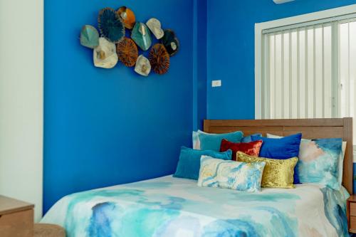 a bedroom with blue walls and a bed with colorful pillows at Cozy Modern 2BR Loft, Monterrazas, Cebu City in Baksan