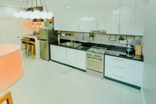 a kitchen with white cabinets and a refrigerator at Cozy Modern 2BR Loft, Monterrazas, Cebu City in Baksan