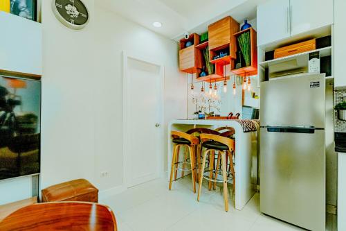 a kitchen with a refrigerator and bar stools at Cozy Modern 2BR Loft, Monterrazas, Cebu City in Baksan